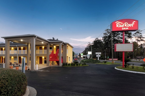 A Red Roof Inn with a two-story building, a covered parking area, and a red sign.