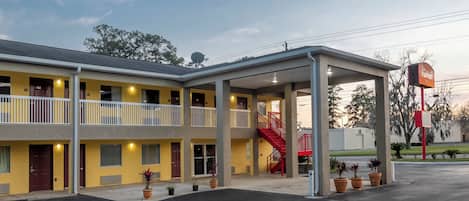Un motel con estacionamiento techado, varios balcones y una escalera roja.
