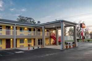 A motel with a covered parking area, multiple balconies, and a red staircase.