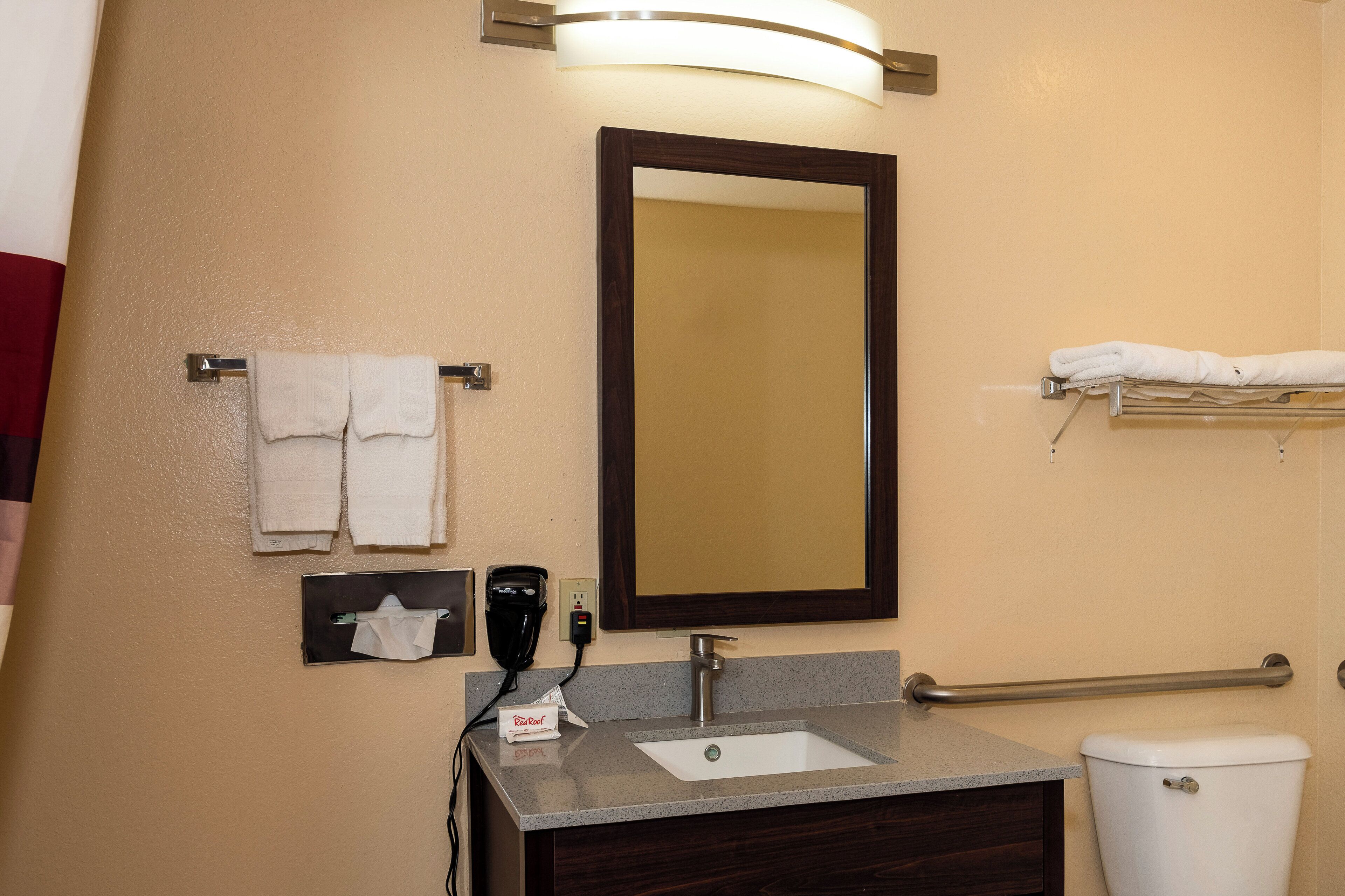 A bathroom with a sink, mirror, towel rack, and a hand dryer.
