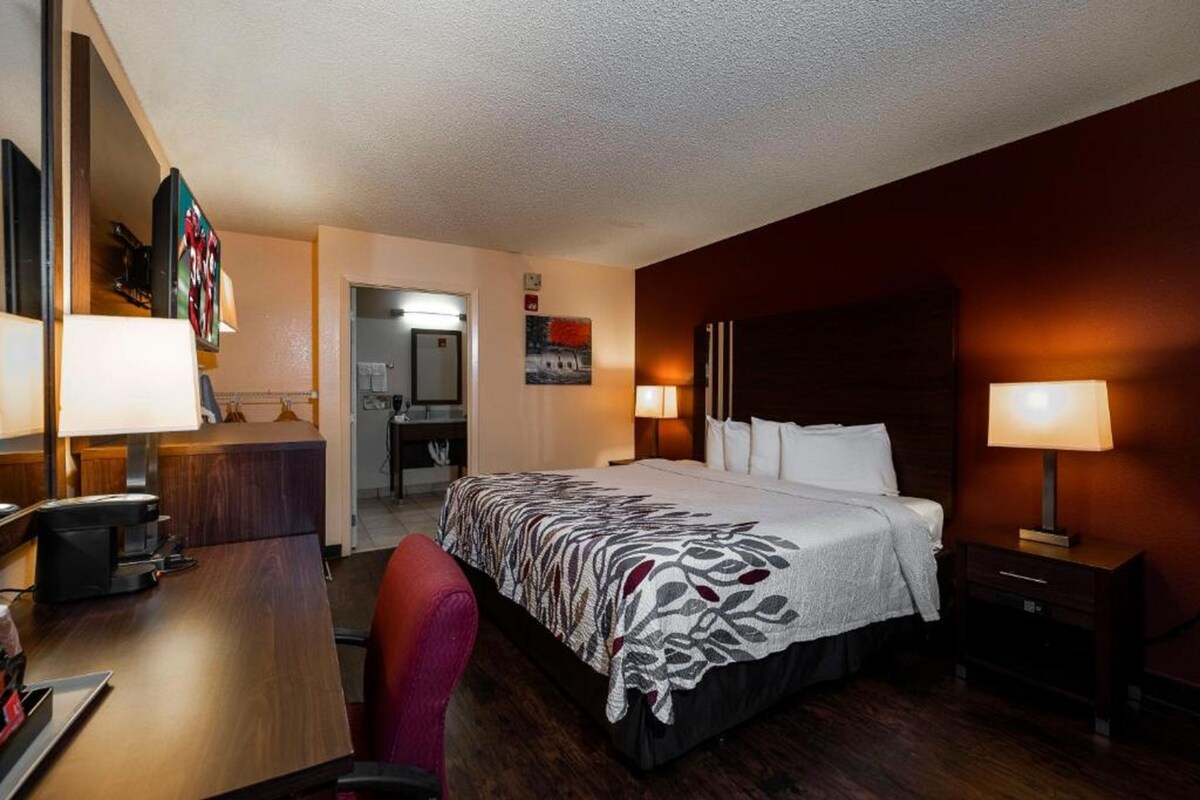 Habitación de hotel con cama, escritorio, silla y mesitas de noche.