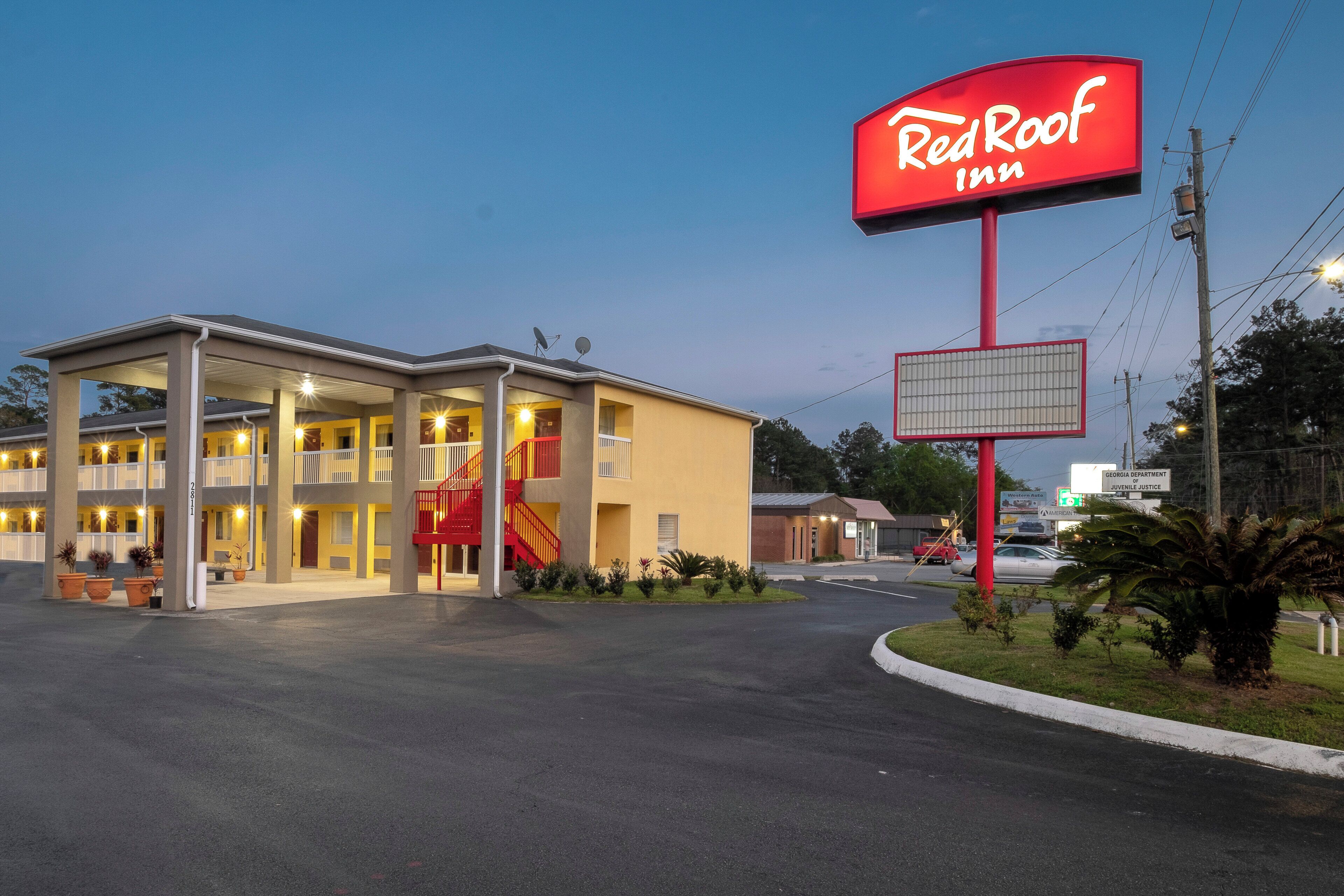 A Red Roof Inn with a two-story building, a covered parking area, and a large illuminated sign.
