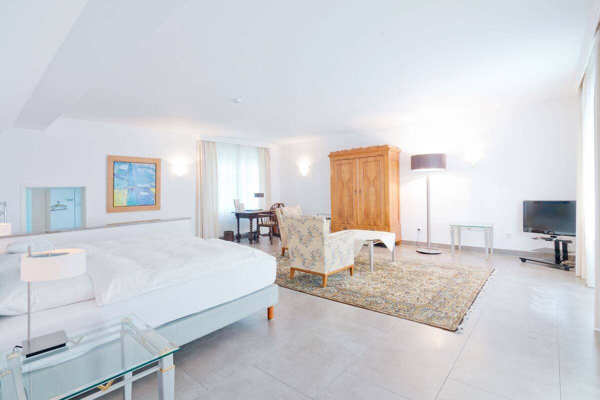 Una habitación de hotel moderna con una cama grande, un escritorio, una silla, un televisor y un armario.