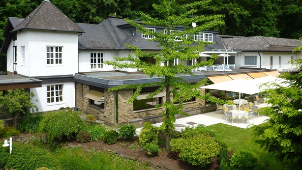 A large, multi-story house with a spacious patio area and a well-maintained garden. - Romantik Waldhotel Mangold (Bergisch Gladbach)