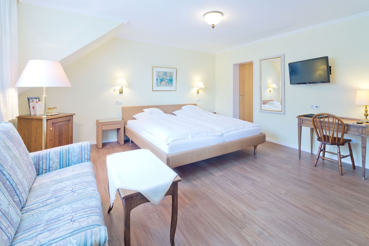 Una habitación de hotel con cama, sofá, escritorio, silla y televisión.