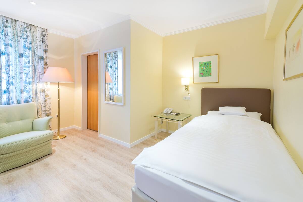 Una habitación de hotel con una cama, un sofá, un escritorio con una lámpara y un teléfono.