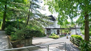A traditional building with a garden area, a pathway, and a wooden fence. - Romantik Waldhotel Mangold (Bergisch Gladbach)