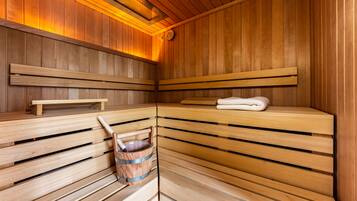 A sauna with wooden benches, a towel, and a wooden bucket.