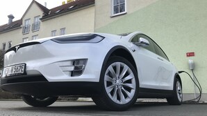 A white Tesla Model S parked on a street with a charging station nearby. - AKZENT Hotel Frankenberg (Frankenberg)