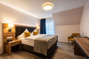 Ein Hotelzimmer mit Bett, Nachttisch, Lampe und Schreibtisch mit Stuhl.