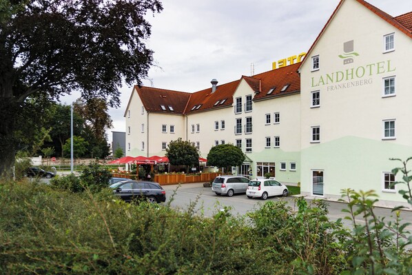 Ein mehrstöckiges Hotel im traditionellen europäischen Stil, mit einem markanten Schild für das Landhotel Frankenberg.