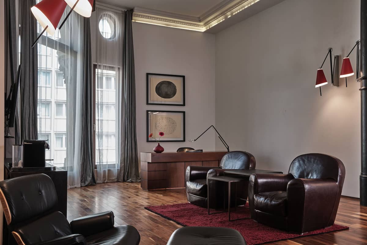 A modern living room with leather furniture, a red rug, and artwork on the wall.