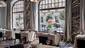 A restaurant with tables set for dining, large windows with curtains, and a view of the street outside. - The Monopol Hotel (Wroclaw)