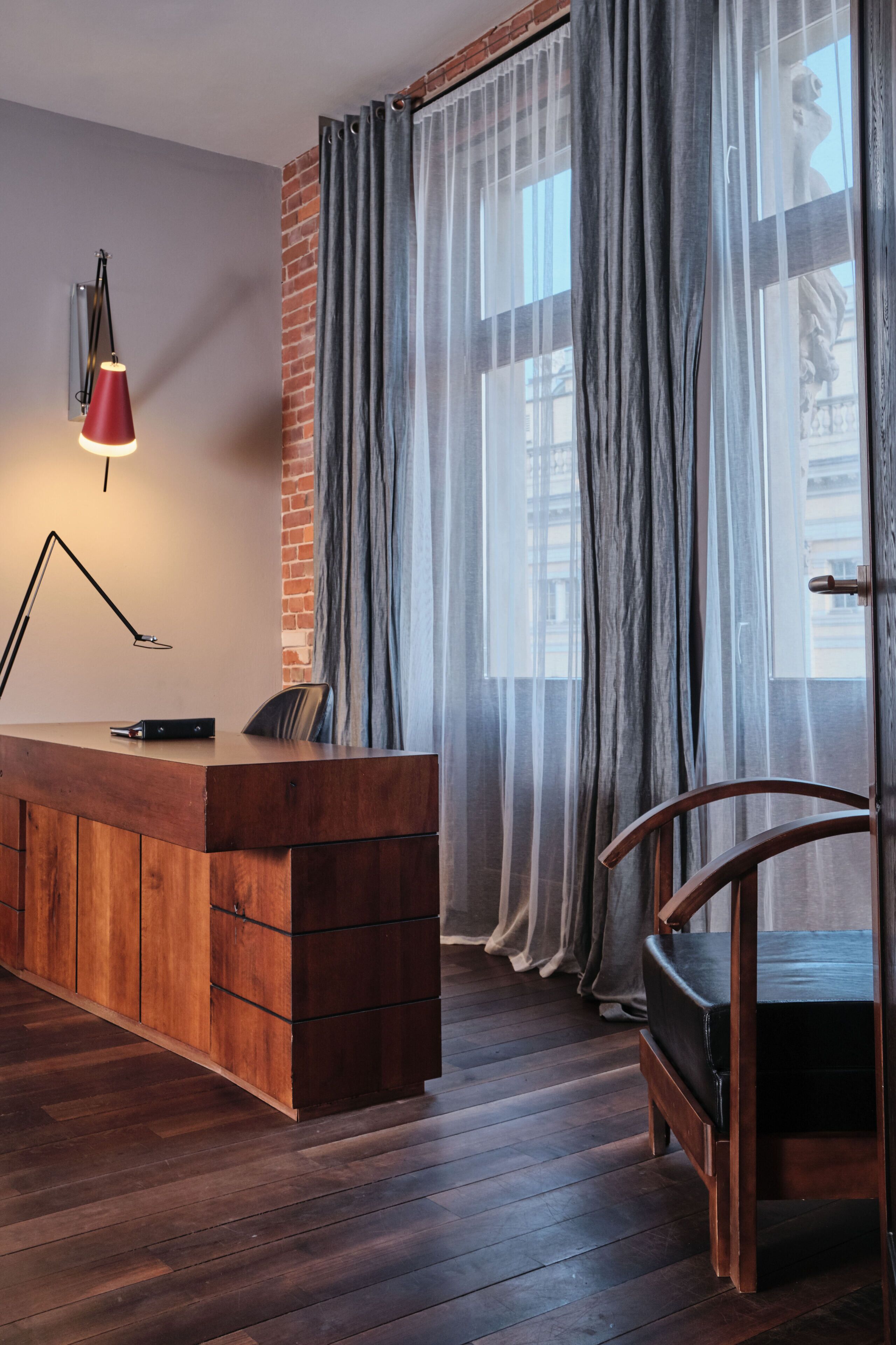 A modern room with a wooden desk, a red lamp, and a chair.