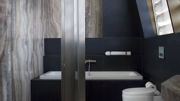 Un baño moderno con pared de mármol, cabina de ducha de cristal y un ventanal grande.