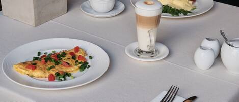 A table set for breakfast with plates of food, a coffee cup, and a glass of milk.