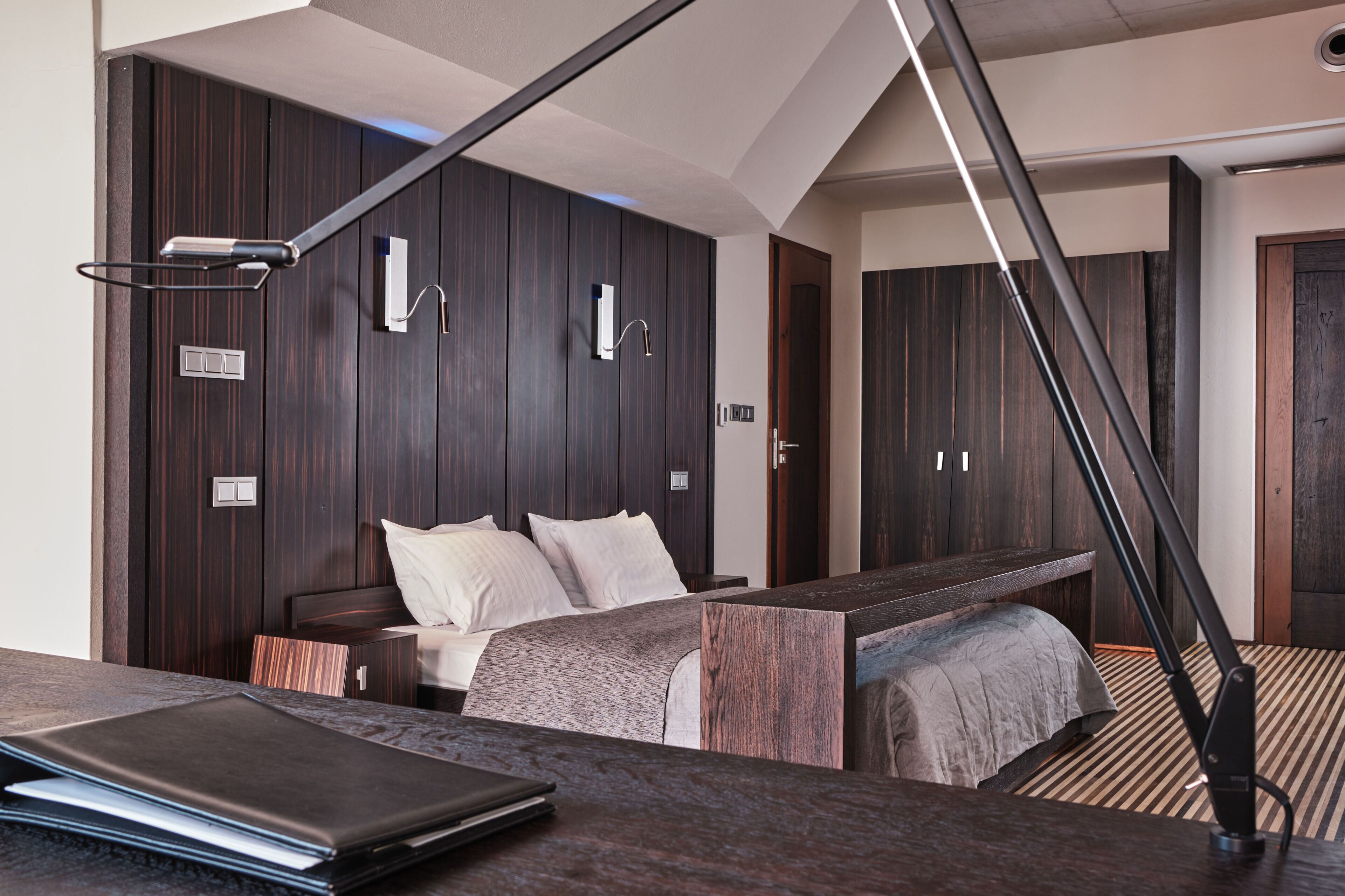 Une chambre moderne avec un lit, des tables de chevet, un bureau et une grande fenêtre.