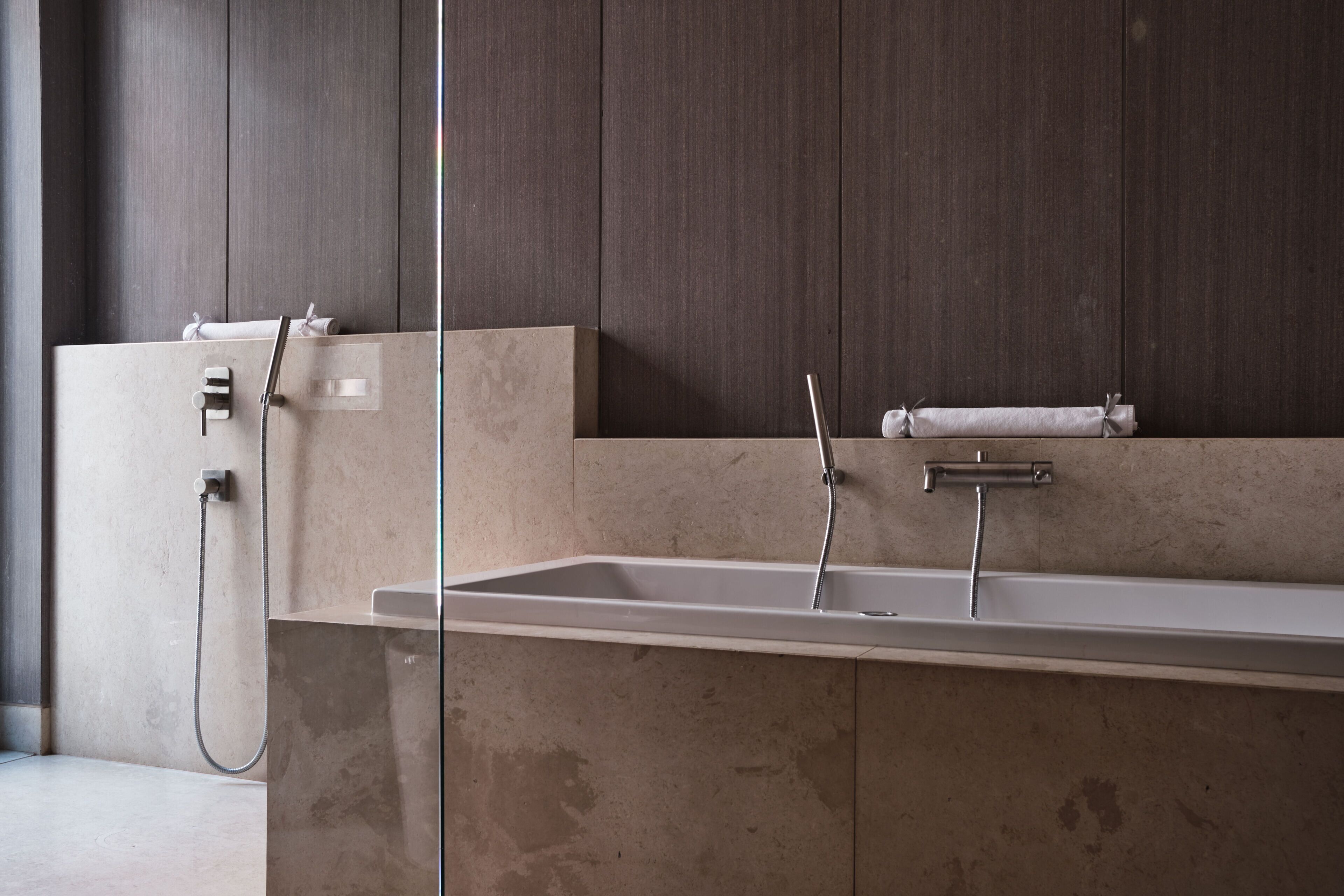 Un baño moderno con un lavamanos rectangular grande, un cabezal de ducha de mano y un perchero para toallas.