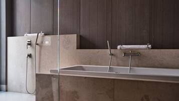 Un baño moderno con un lavamanos rectangular grande, un cabezal de ducha de mano y un perchero para toallas.