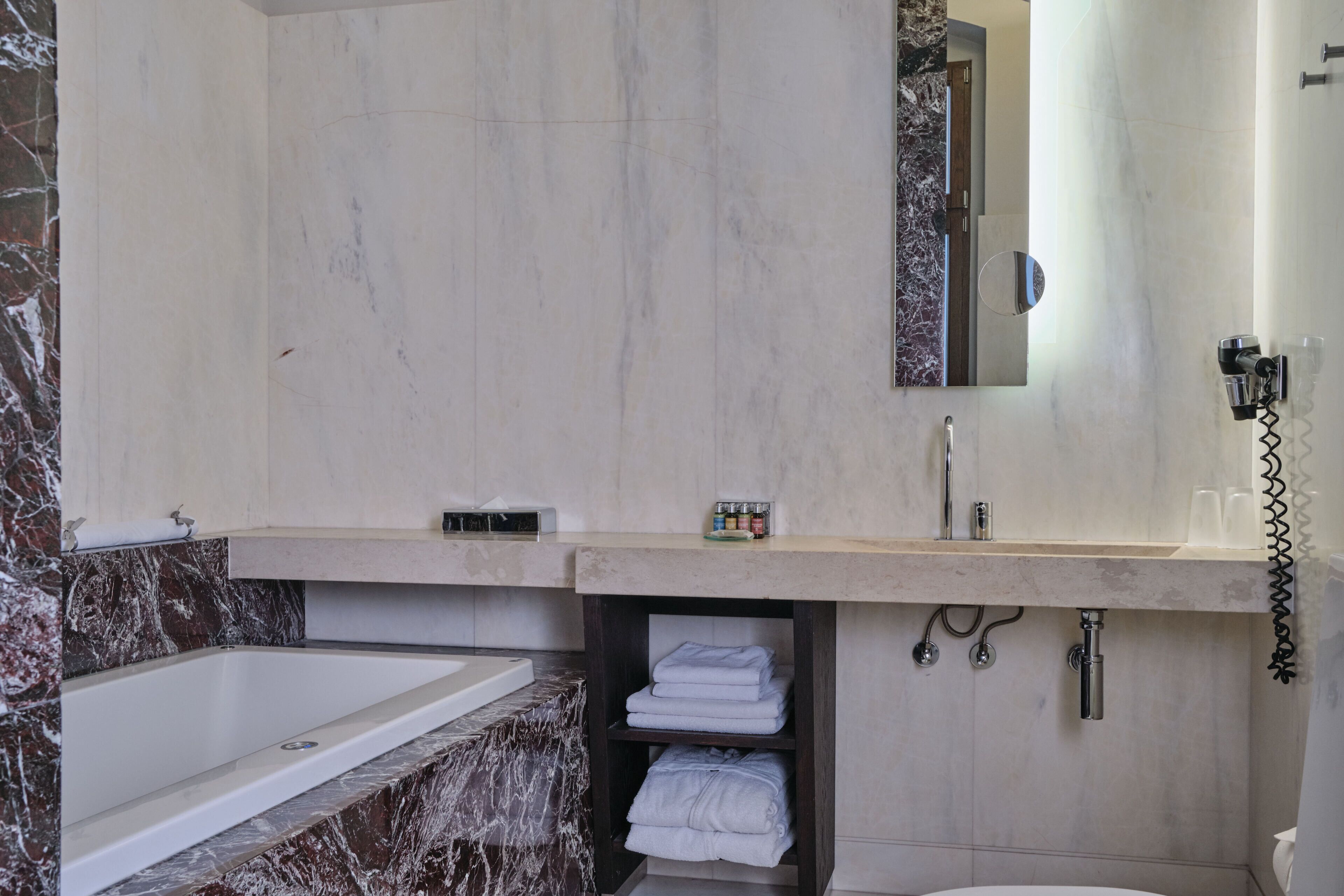 Un baño moderno con bañera, lavamanos, espejo y perchero para toallas.