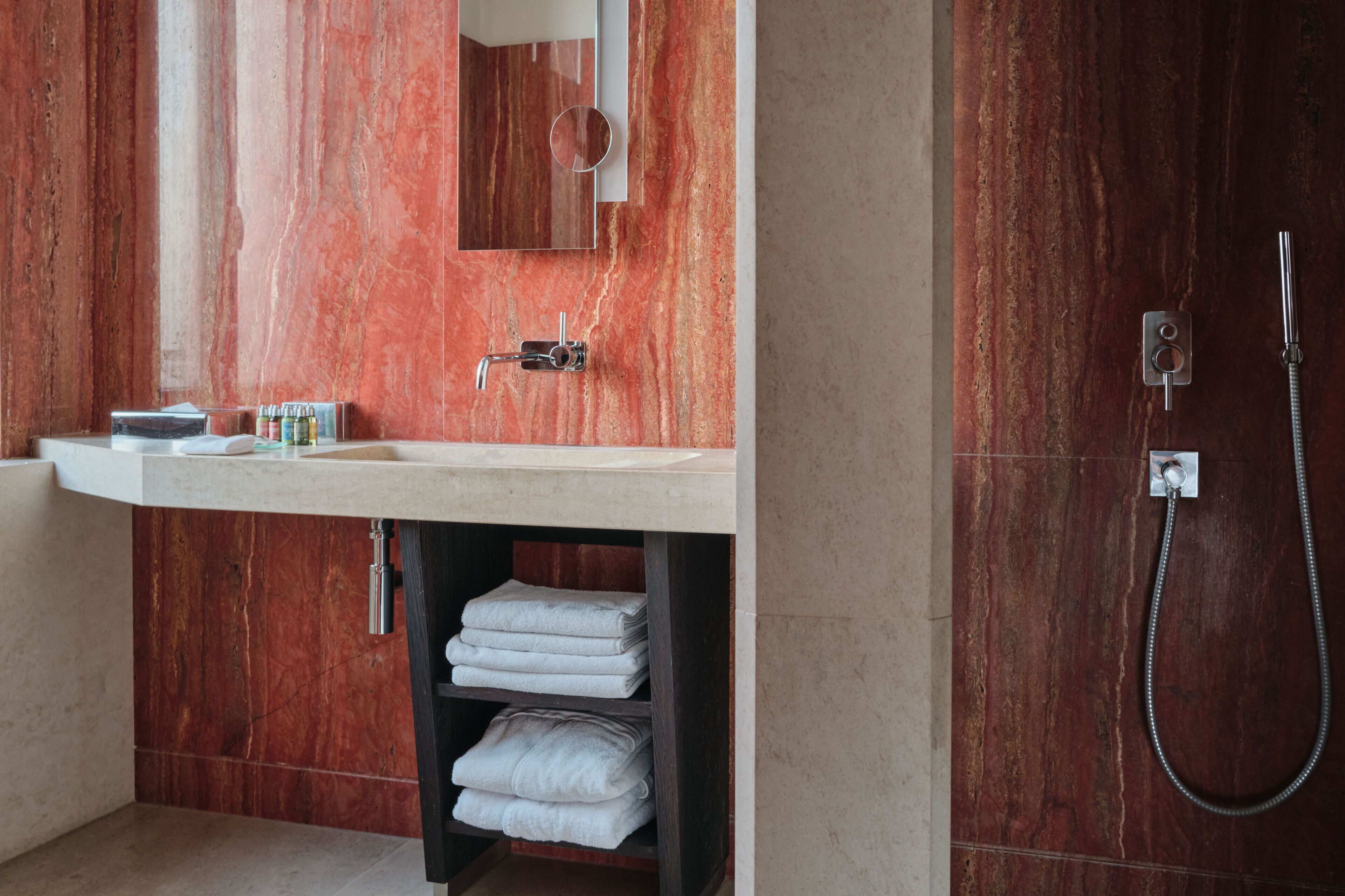 A bathroom with a marble vanity, a mirror, a towel rack, and a shower.