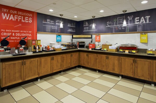 A kitchen area with waffle makers, a toaster, and various food items on the counter.