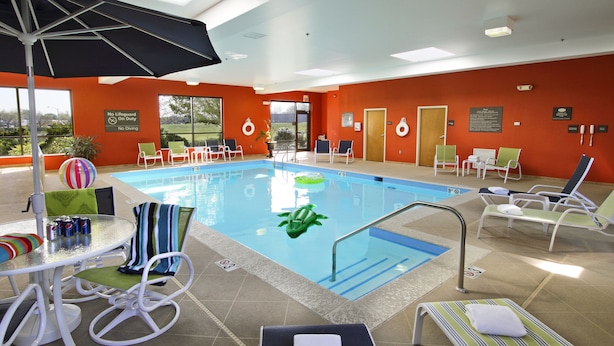 Ein Poolbereich mit Liegestühlen, einem Tisch mit Getränken und Blick ins Freie.