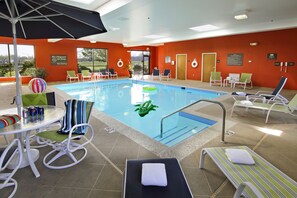 A swimming pool area with lounge chairs, a table with drinks, and a view of the outdoors. - Hampton Inn Hagerstown-I-81 (Hagerstown)