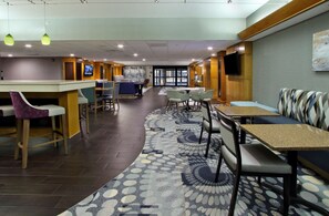Un vestíbulo de hotel con recepción, zona de estar y una pantalla de televisión.