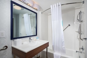 Bathroom features a large mirror, sink, and vanity, along with a shower area and geometric patterned walls.