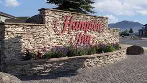 A stone wall with the sign "Hampton Inn" and a mountain in the background.