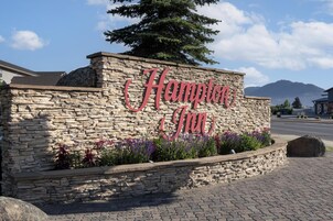 Un muro de piedra con el letrero "Hampton Inn" y una montaña al fondo.