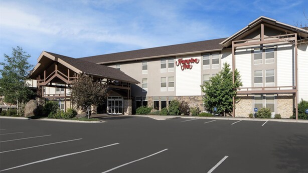 A Hampton Inn hotel with a modern design, featuring a large parking lot and a welcoming entrance.