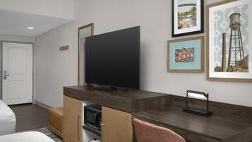 A hotel room with a wooden desk, a television, a microwave, and a small seating area.
