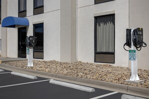 Une borne de recharge pour voitures électriques, avec un panneau indiquant qu’elle est réservée au stationnement des voitures électriques pendant la recharge.