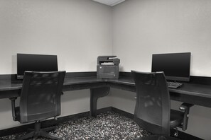 Une salle de conférence avec une longue table, deux chaises et deux écrans d’ordinateur.