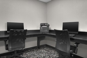 Un salón de conferencias con una larga mesa, dos sillas y dos monitores de ordenador.