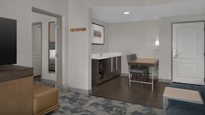 A modern living room with a flat-screen TV, a brown sofa, a small table, and a blue armchair. - Hampton Inn & Suites Greenville/Spartanburg I-85, SC (Duncan)