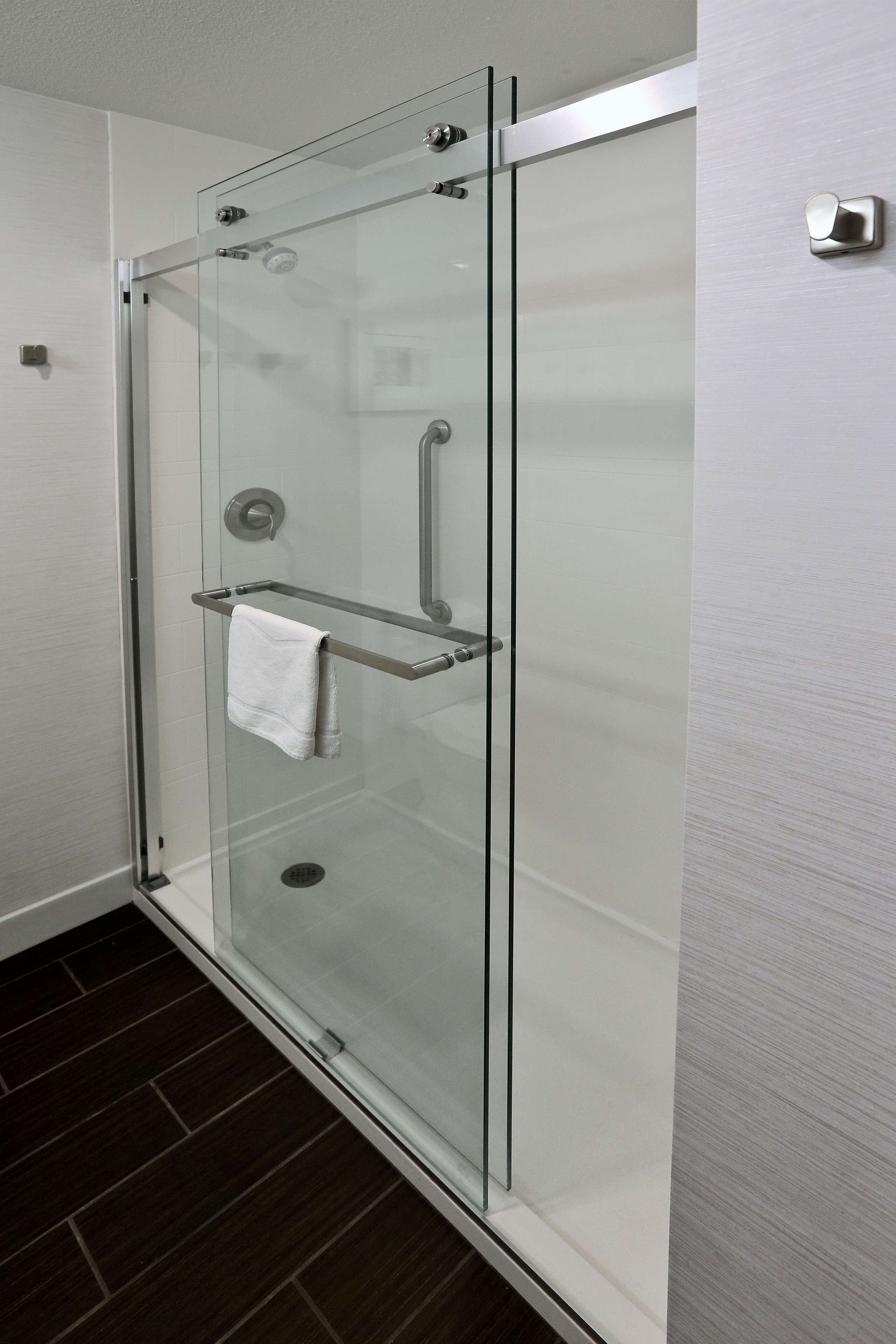 A glass-enclosed shower with a towel rack and a visible drain.