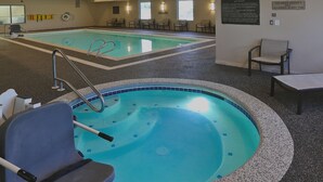 Una piscina interna con una postazione di salvataggio, una scala per la piscina e un cartello che vieta l'accesso ai bambini sotto i 5 anni nella vasca idromassaggio.