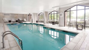 An indoor swimming pool with clear water, surrounded by lounge chairs and tables, large windows, and a tiled floor. - Hampton Inn & Suites Dallas-DFW Airport North-Grapevine (Grapevine)