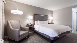 A hotel room with a large bed, a chair, bedside tables, lamps, and a headboard. - Hampton Inn & Suites Dallas-DFW Airport North-Grapevine (Grapevine)