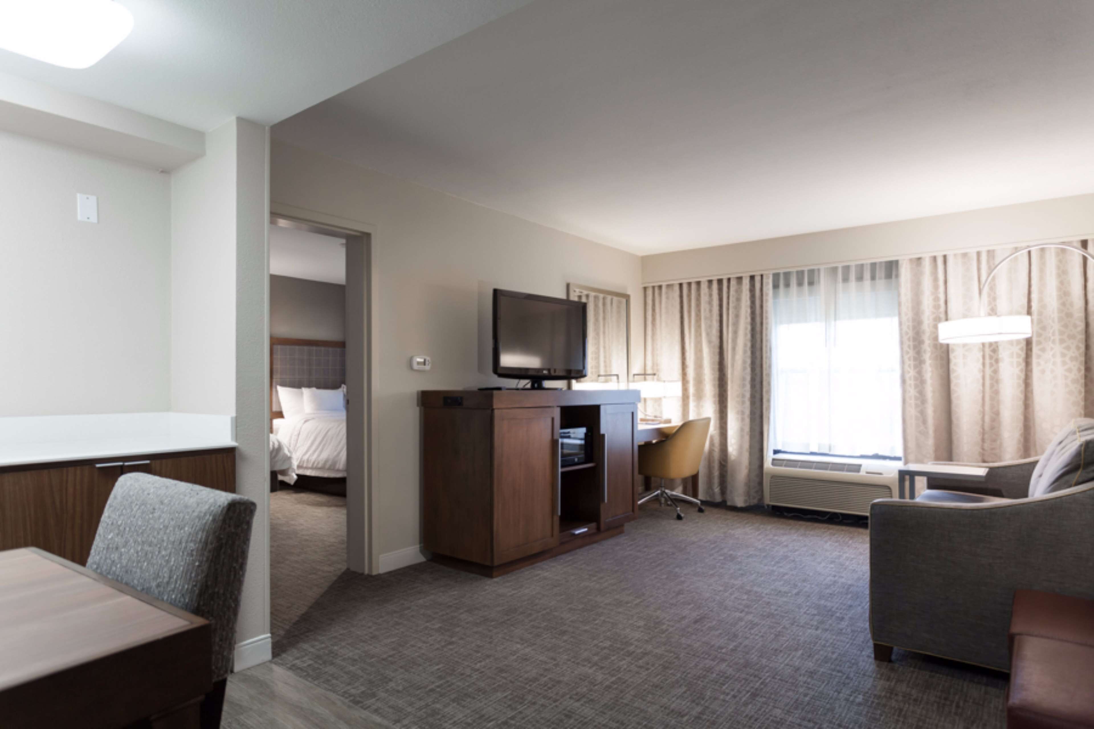 A hotel room with a bed, a desk with a computer, a television, a chair, and a couch.