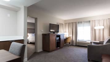 A hotel room with a bed, a desk with a computer, a television, a chair, and a couch.