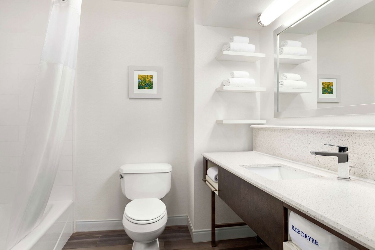 A modern bathroom with a white toilet, a sink, a mirror, and a shower.