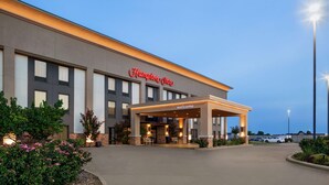 Un hotel Hampton Inn con entrada cubierta y aparcamiento.