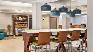 Un comedor moderno con una mesa larga, sillas de metal e iluminación colgante.