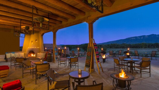 An outdoor patio with seating, a fireplace, and a view of the mountains at dusk. - Hyatt Regency Tamaya Resort & Spa (Santa Ana Pueblo)