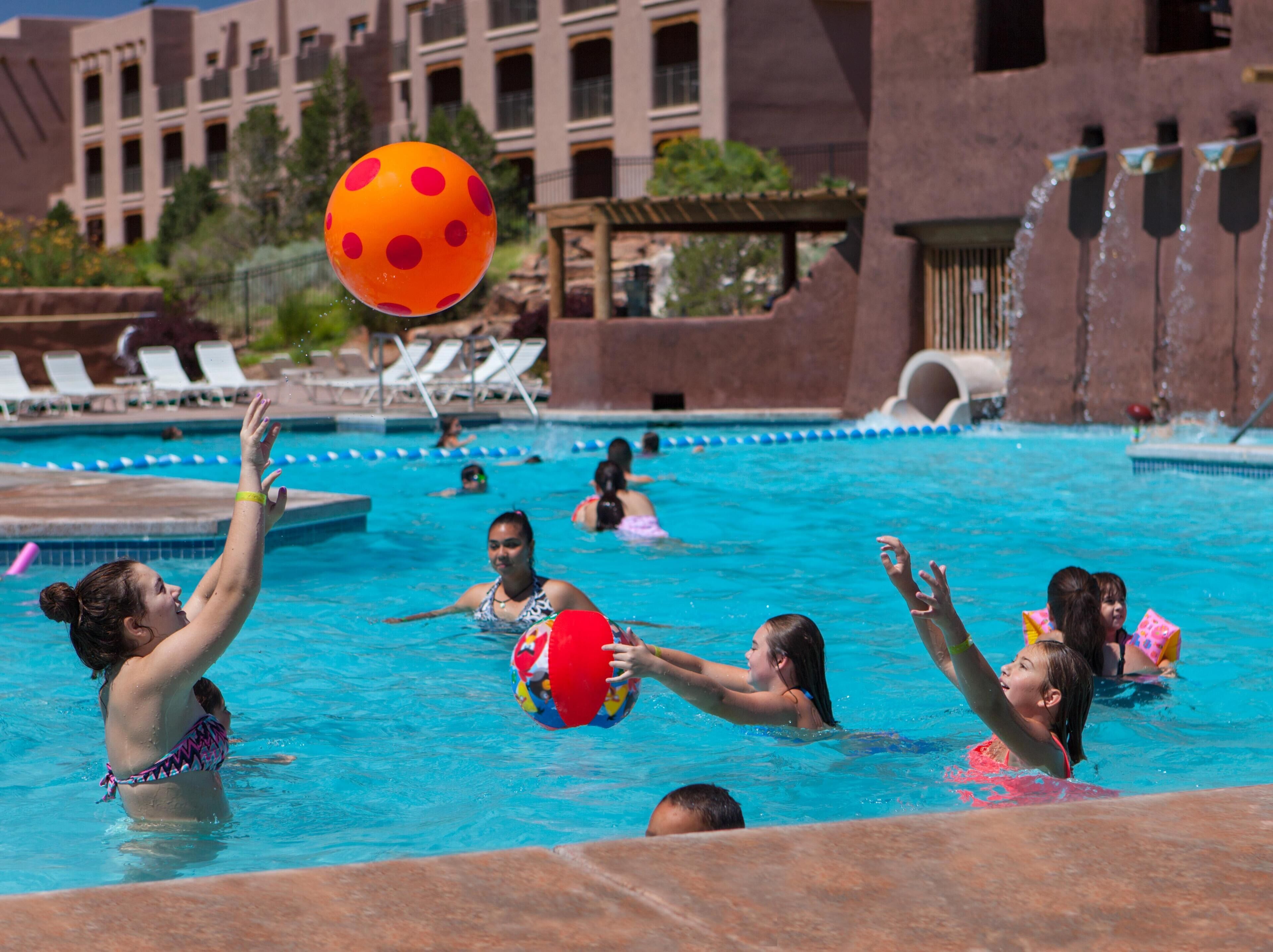 Une zone autour d’une piscine où plusieurs personnes jouent au ballon.