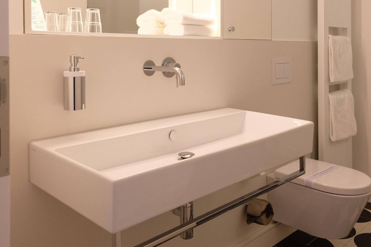 A modern bathroom with a white sink, mirror, and toilet.
